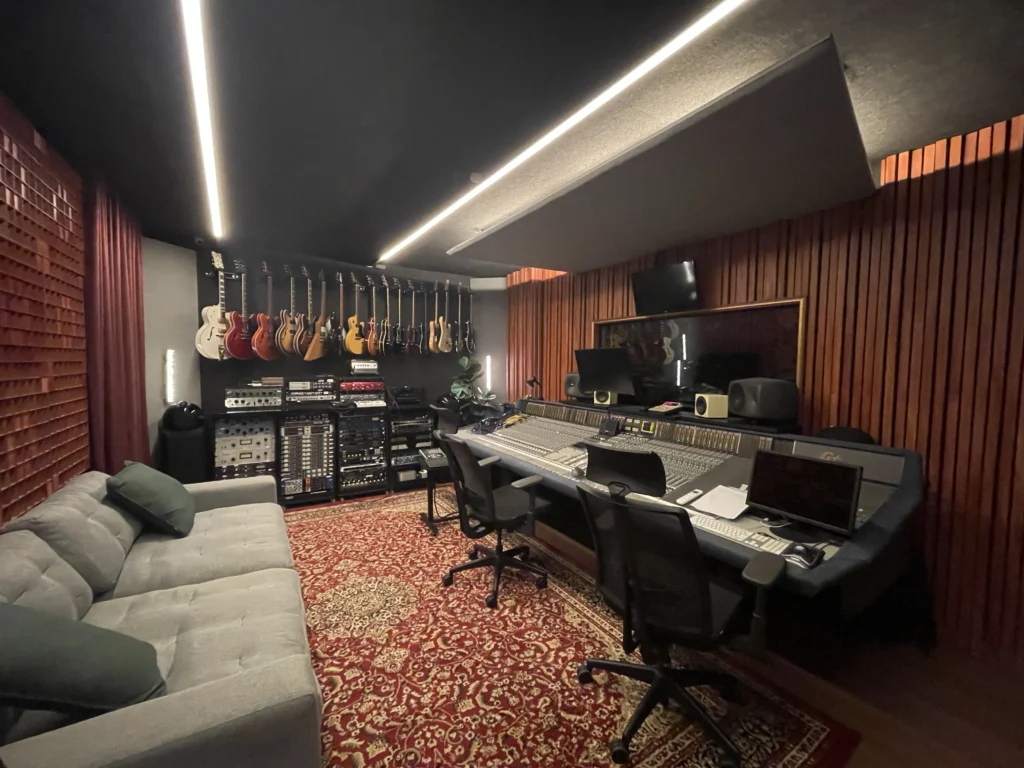 Sala de controle do estudio da Valetes Records em Bauru, com mesa de mixagem e parede de guitarras